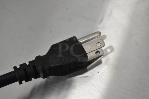 Black three-prong power plug on metal surface, part of a scratch and dent commercial kegerator, 115 volts, 1 phase.