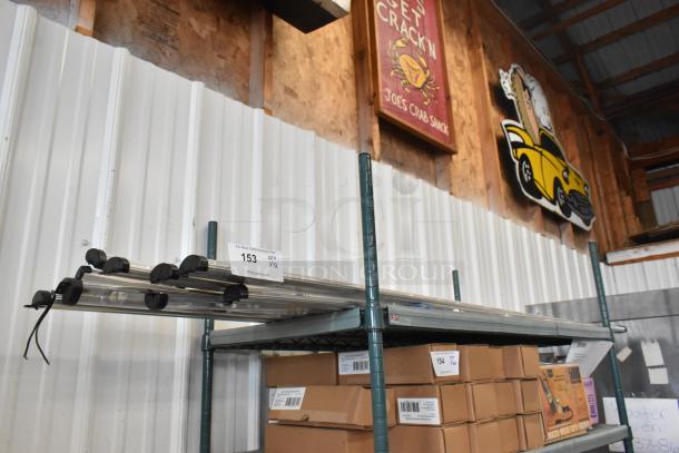 12 Anthony Optimax 2 LED light strips on metal shelf. Includes label: "153 QTY 1/2". Auction item in storage condition.