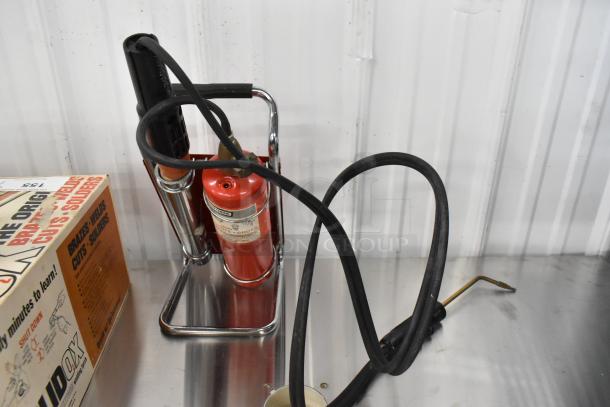 Sears 5000 welding torch, includes red cylinder and hoses, mounted on a chrome stand. Slight wear visible on handle.