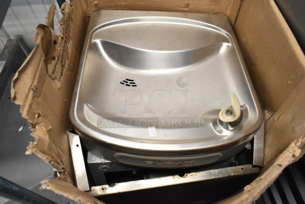Brand new Elkay EZSTL8SC wall mount bi-level cooler in original packaging. Slight scratches and dents visible; ADA compliant.