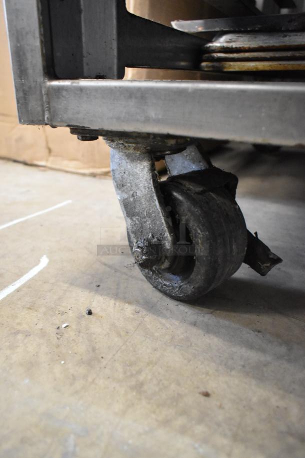 Baxter stainless steel commercial oven caster showing dual pan rack with heavy-duty wheel, slightly worn condition.