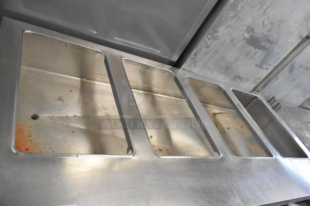 Stainless steel commercial electric steam table with four compartments, 208 volts, shows signs of use, ideal for catering.