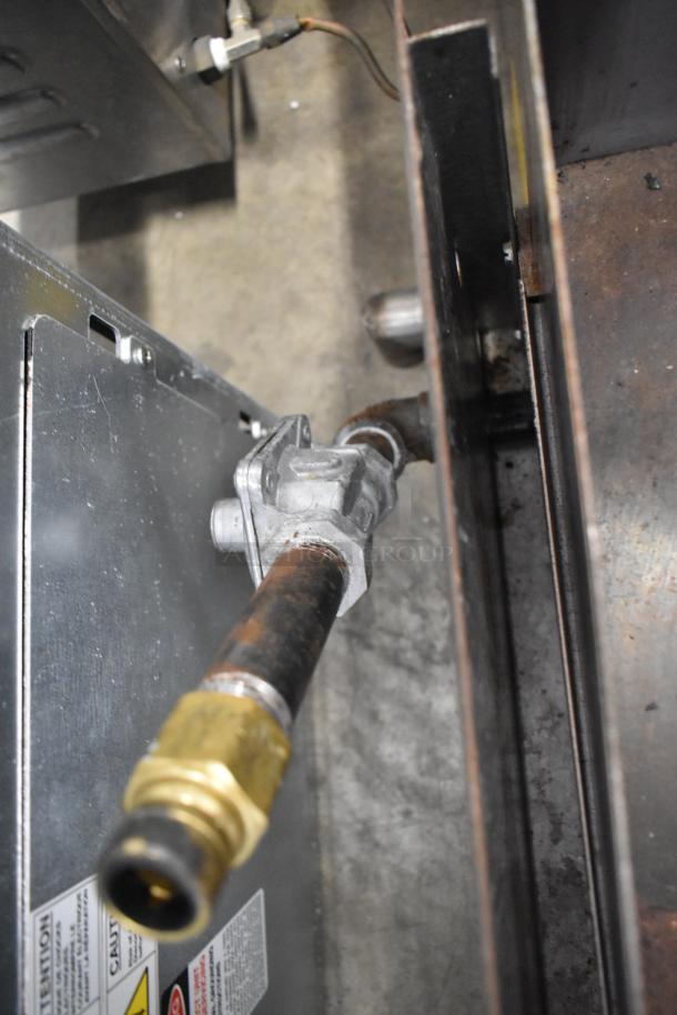 Close-up of natural gas connection on Imperial ITS-24 stainless steel commercial flat top griddle. Labels visible, detailing safety warnings.