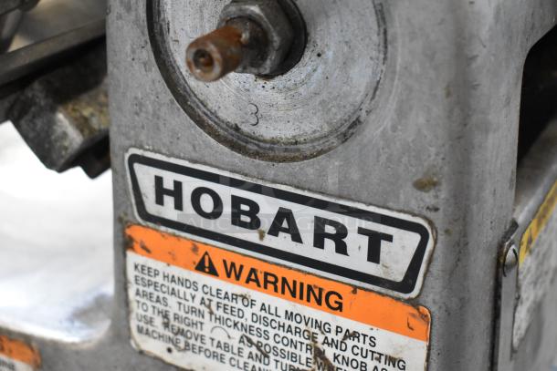 Hobart 1612 stainless steel commercial meat slicer, 115 volts, 1 phase. Visible Hobart branding and safety warning label.