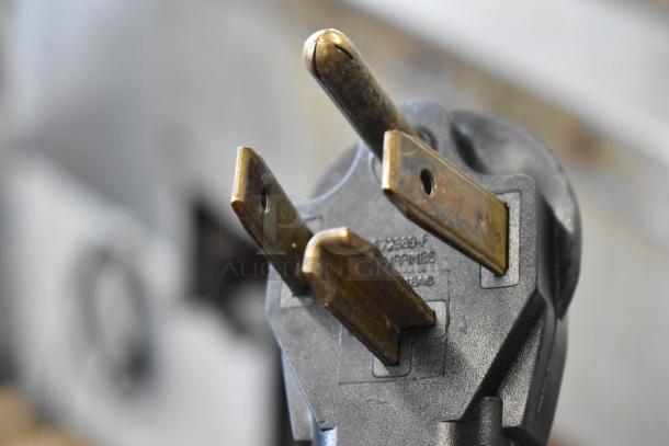 Close-up of an electrical plug, not the Alto Shaam Halo Heat oven. Plug features three prongs and markings.