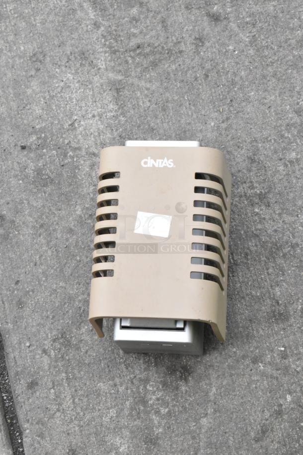 Cintas paper towel dispenser with beige cover, features visible logo and a small label, in used condition.
