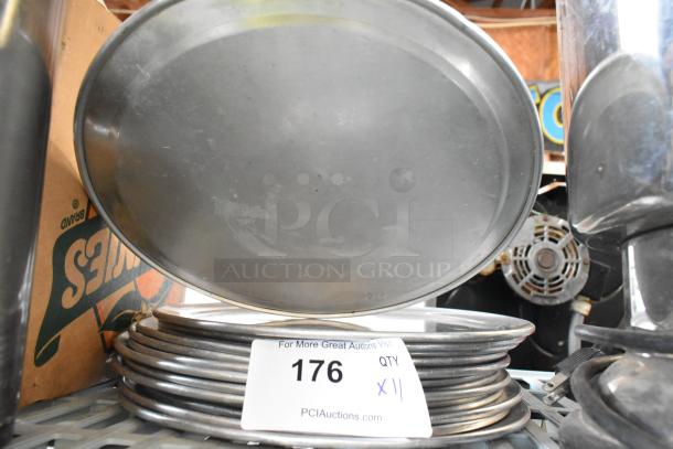 11 round metal baking pans, stacked, showing mild wear. Auction label reads "176 QTY x11" from PCI Auctions.