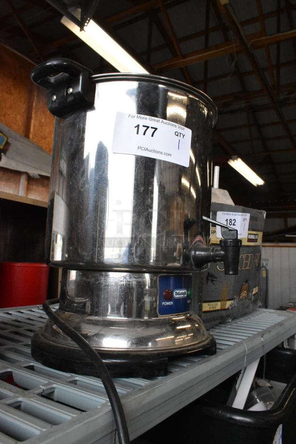 DeLonghi stainless steel countertop automatic coffee maker, with visible power indicator and handle, in used condition.