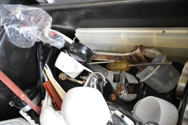 Lot of mixed items including utensils and tools in a black poly bus bin. Includes wrench, screwdriver, and cups. Mixed condition.