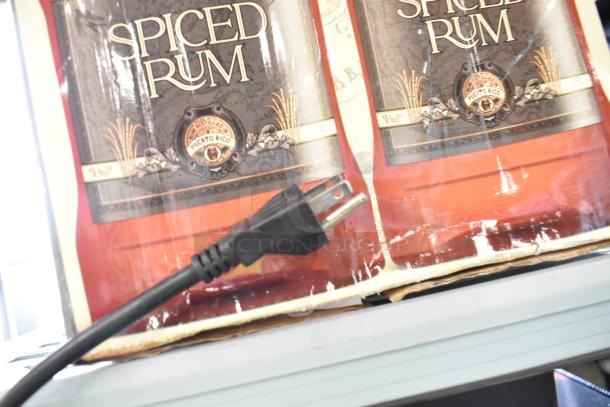 Lot with various items, including a McCann's tank and cardboard boxes labeled "Spiced Rum." Includes an electrical plug.