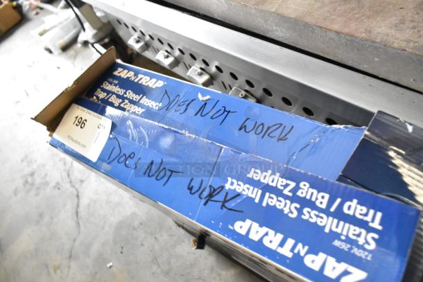 Zap n Trap Bug Zapper in open box, marked "DOES NOT WORK." Stainless steel, 120 Volts, 1 Phase. Auction tag visible.