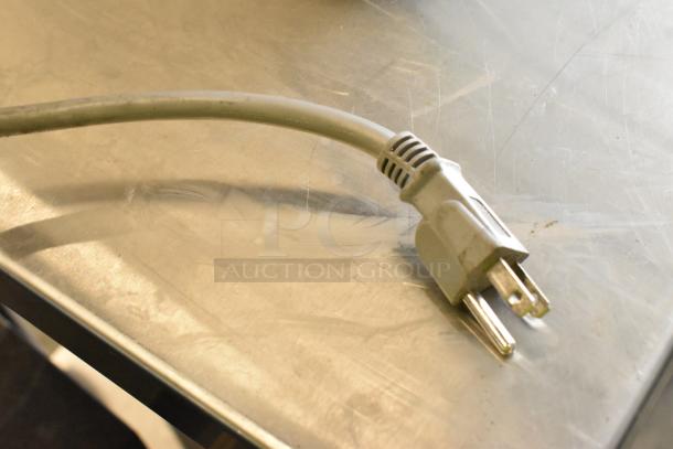 Close-up of a power cord for a 2023 Solwave 180MW112T Commercial Microwave, resting on a stainless steel surface.
