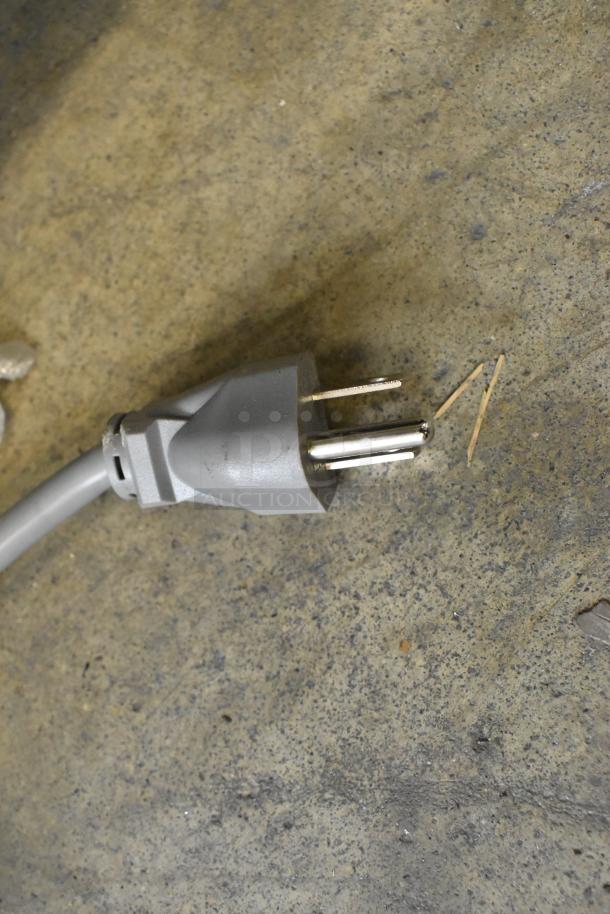 Gray power plug on a rough concrete surface, part of the Winco Spectrum EMW-1000ST commercial microwave.