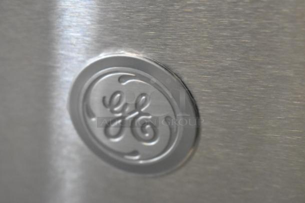 General Electric stainless steel logo on the brand new JVM3160RF9SS microwave, minor scratch visible.
