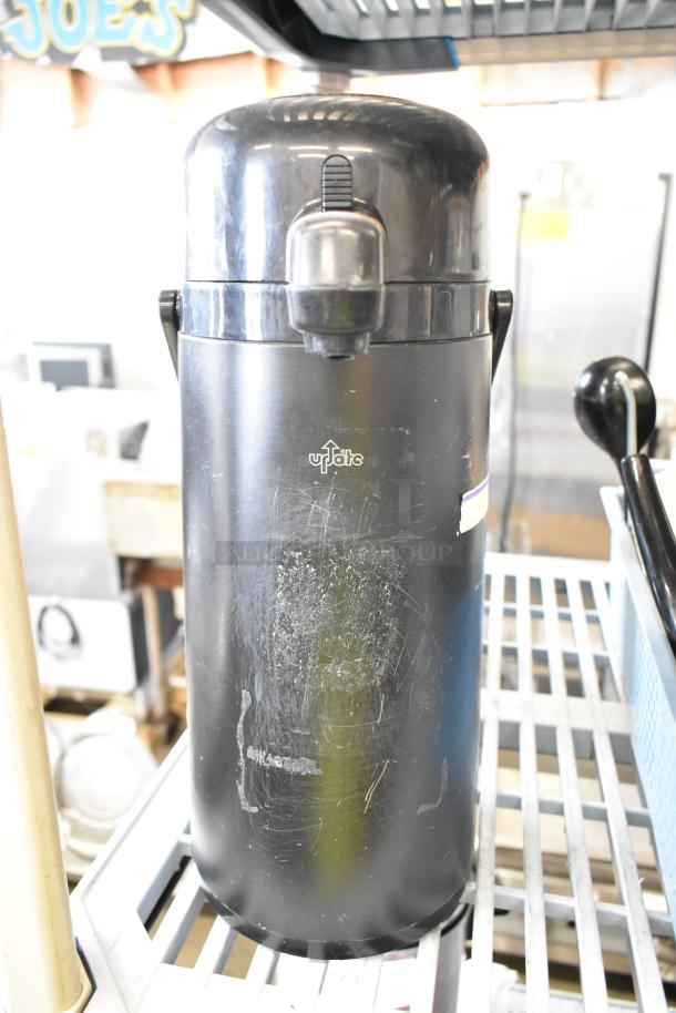 Black air pot, brand "Update," visible wear on surface, lever lid, ideal for beverages, auction includes two units.