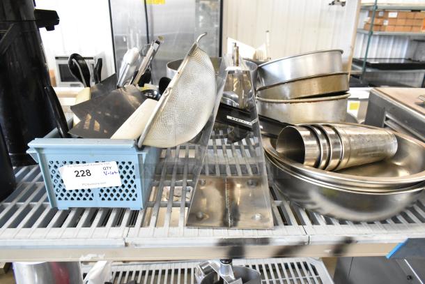 Alt text: Collection of metal bowls, mixing cups, baking pans, and utensils in used condition on a shelf, tagged as auction lot 228.