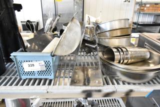 Alt text: Collection of metal bowls, mixing cups, baking pans, and utensils in used condition on a shelf, tagged as auction lot 228.