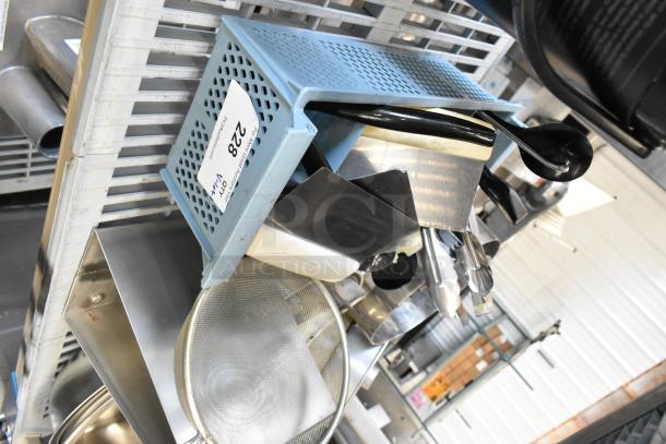 Assorted metal kitchenware including bowls, mixing cups, baking pans, and utensils. Includes labeled blue storage bin.