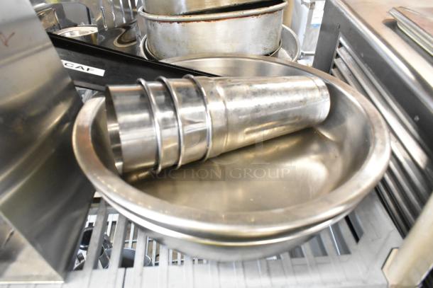 Lot of metal bowls, mixing cups, round baking pans, and utensils in used condition. Ideal for kitchen tasks.