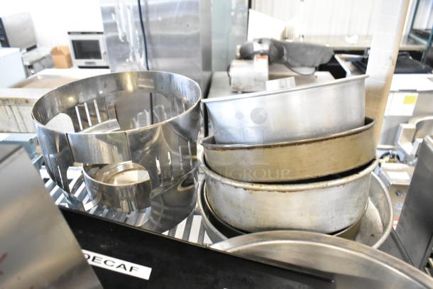 Lot of metal bowls, mixing cups, round baking pans, and utensils. Varied sizes. Used condition with some wear.