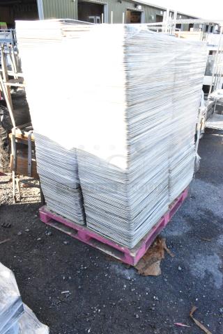Pallet of metal full-size baking pans, stacked and wrapped, on a pink pallet outdoors. Appears in good condition.
