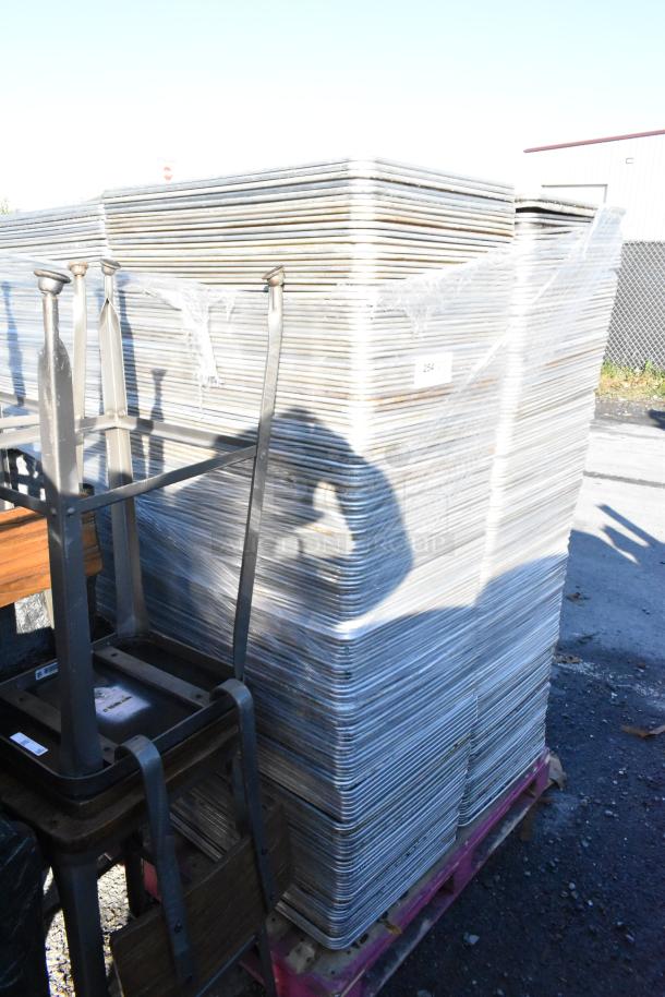Stacked metal full-size baking pans on a pallet, wrapped in plastic. Visible label marked "254". Used condition.