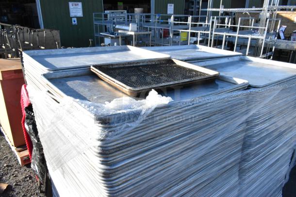 Pallet of metal full-size baking pans, stacked and shrink-wrapped. Used condition with visible wear. Ideal for bulk use.