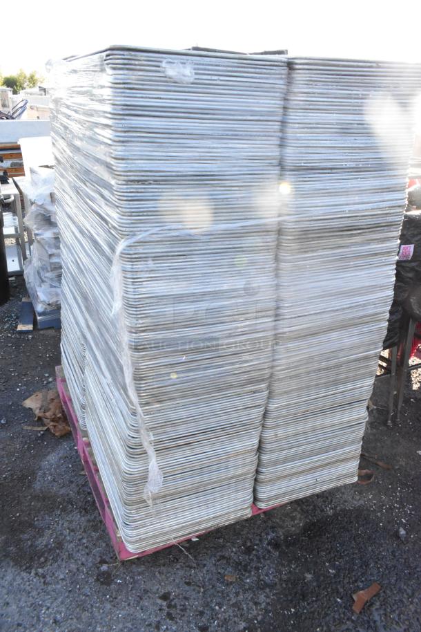 Pallet of metal full-size baking pans stacked and wrapped. Some signs of wear. Ideal for bulk purchase or commercial use.
