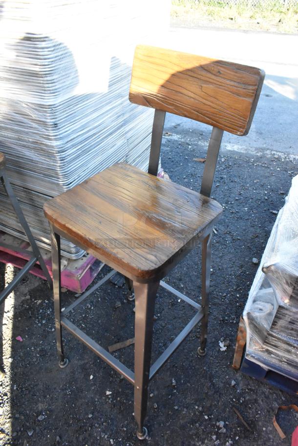 30 metal bar-height chairs with wooden backrests and seats, shown in good condition, stacked on pallets outdoors.