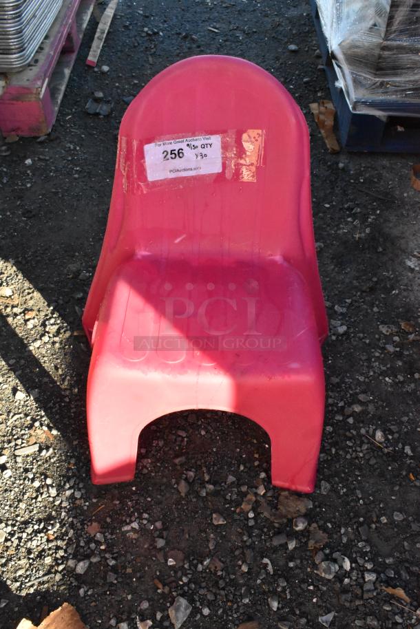 Pink children's chair, plastic, visible tag indicating lot 256, quantity 30, stored on outdoor ground.