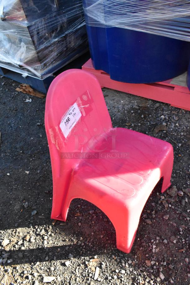 Pink poly children's chair with curved back, showing a label with auction lot number. Durable and stackable design.