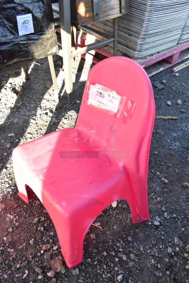 Pink poly children's chair on gravel, showing wear. Label indicates auction lot number "256". 30 chairs available per bid.