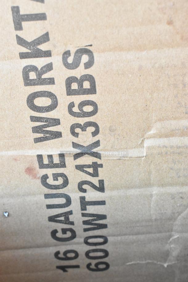 Cardboard box with visible markings "16 GAUGE WORK TABLE, 600WT24X36BS," indicating a Regency stainless steel work table model.