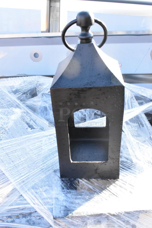 Black wrought iron metal lantern with ring handle. Rectangular shape, open panes. Bundled in protective wrap.