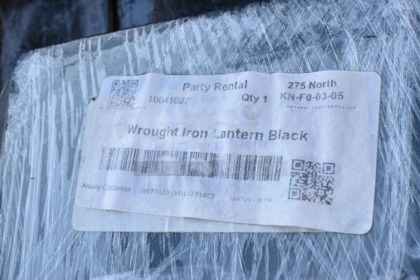 100 black wrought iron lanterns, new condition, wrapped with label indicating "Party Rental" and "Wrought Iron Lantern Black."