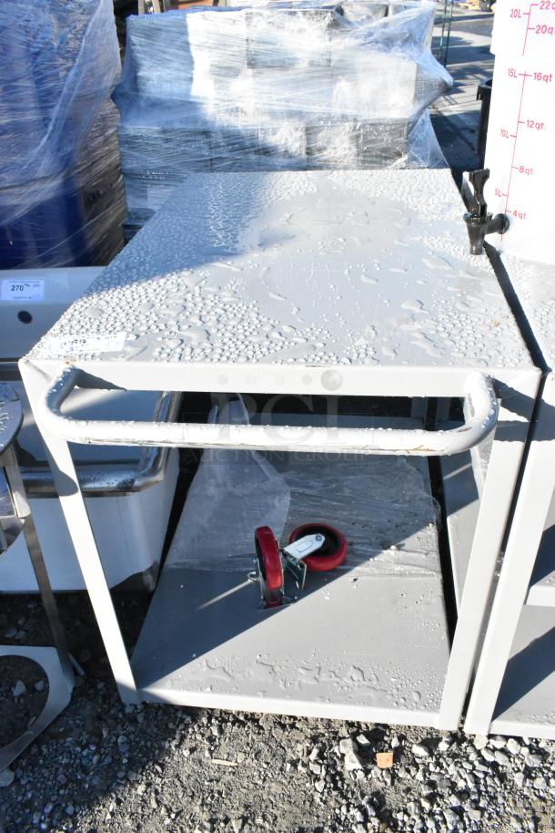 New gray metal 2-tier cart with commercial casters, scratch and dent condition. Visible water droplets on surface.