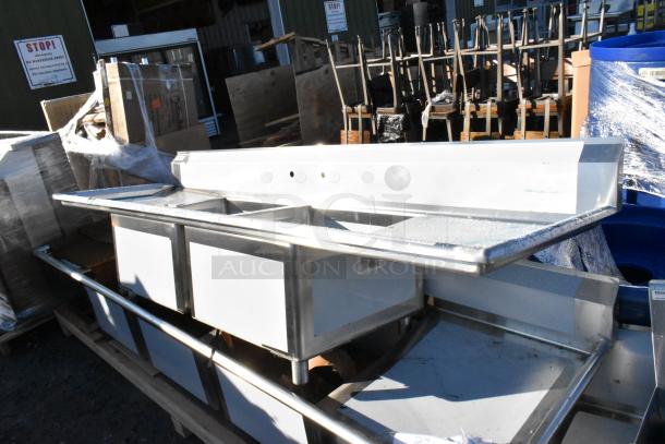 BRAND NEW Regency 600S22424224 stainless steel 2-bay sink with dual drain boards. Scratch and dent condition visible.
