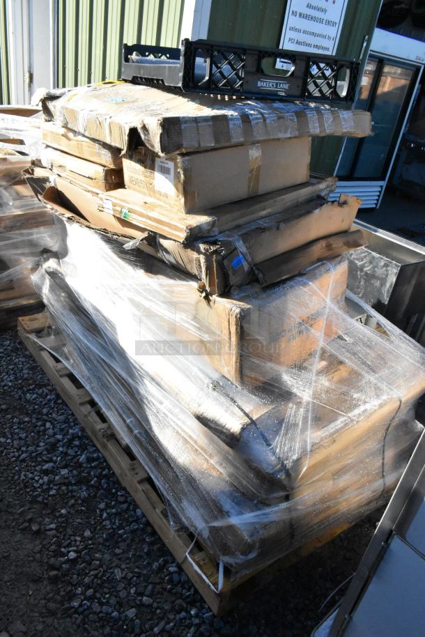 15 brand new scratch and dent items on a pallet, including stainless tables and platform truck, wrapped in plastic.