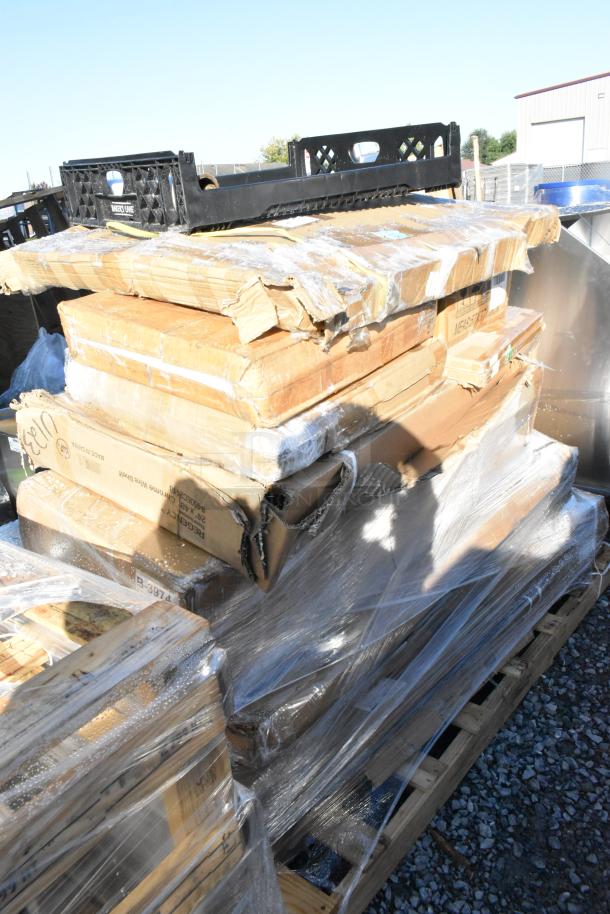 15 brand new scratch and dent items on a pallet, including stainless tables and a platform truck. Boxes wrapped in plastic.