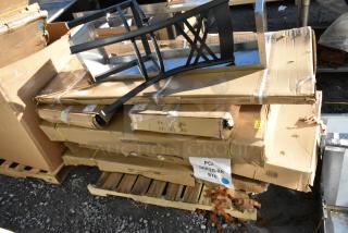 Nine brand new scratch and dent items, including a pan rack and work tables, stacked in original packaging. Signs of wear on boxes.