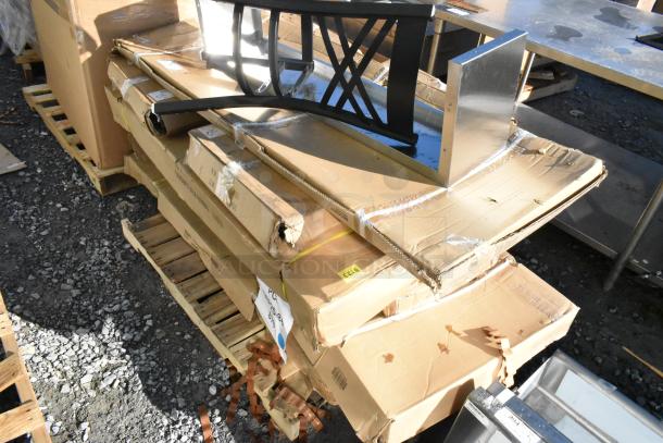 9 brand new scratch and dent items, including a pan rack and work tables, on pallets; damaged boxes visible.