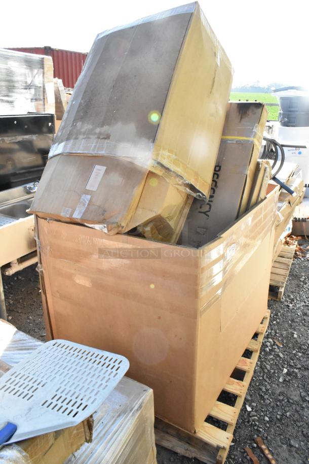 Large cardboard box containing new scratch and dent items, including tabletops and wire rack, on a wooden pallet.