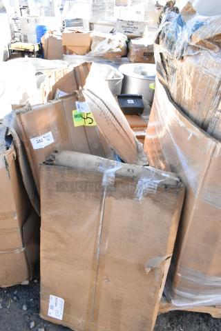 Cardboard boxes containing new scratch and dent items, including a stainless steel utility cart and bar stool. Labels show item codes and condition.