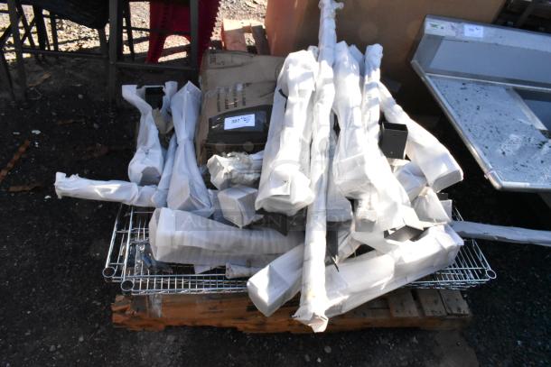 Lot of brand new scratch and dent items, including chrome wire shelves and assorted metal pieces, on a wooden pallet.