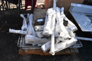 Lot of brand new scratch and dent items, including chrome wire shelves and assorted metal pieces, on a wooden pallet.