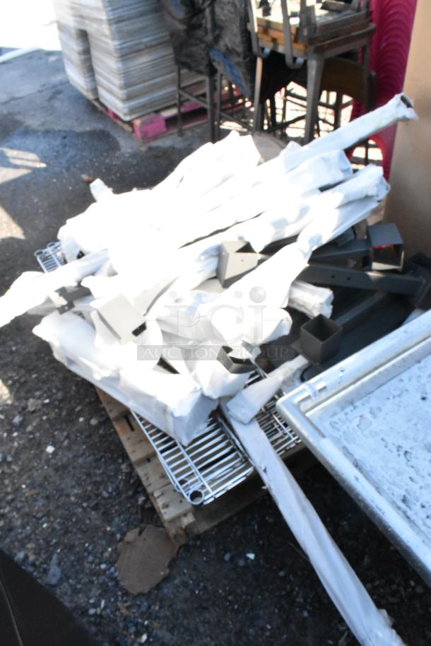 Lot of brand new scratch and dent items, including chrome wire shelves and various metal pieces, on a pallet outdoors.