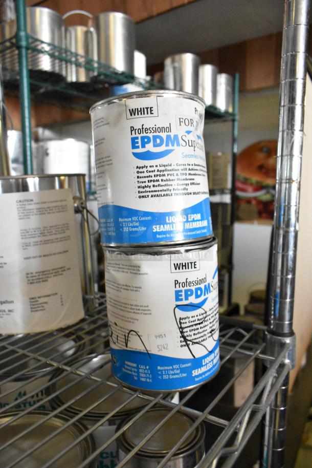 Stacked cans of Pro Guard EPDM White liquid membrane, labeled for seamless roofing, on a metal shelf.