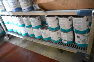 Shelf of 53 Pro Guard chemicals, including 9118 Moisture Cure Liquid Rubber cans, stored in a well-lit area.