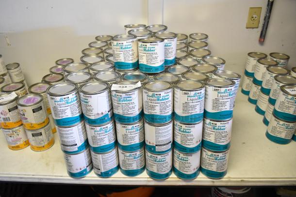 131 cans of Pro Guard 9118 Moisture Cure Liquid Rubber, neatly stacked, showcasing labels with product details.
