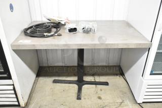 Dining height table with contents including coiled cable and plastic components. Sturdy base; some surface wear visible.